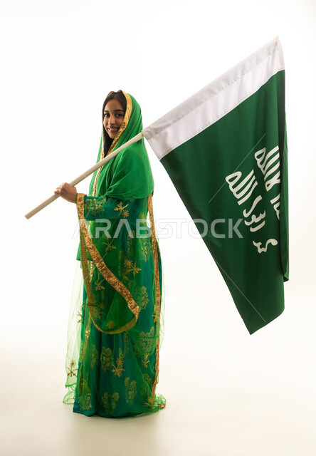 امرأة سعودية بالزي التقليدي تحمل علم السعودية