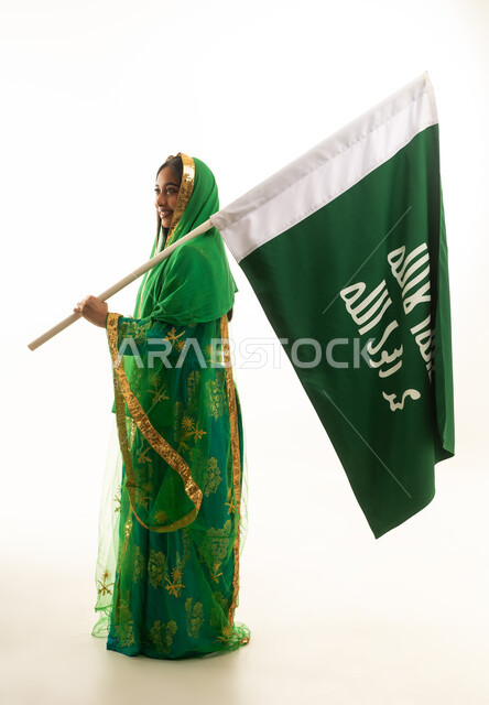 امرأة سعودية تحمل العلم الوطني بالزي التقليدي