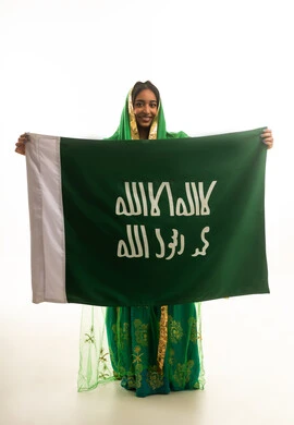 امرأة سعودية تحمل العلم الوطني بالزي التقليدي