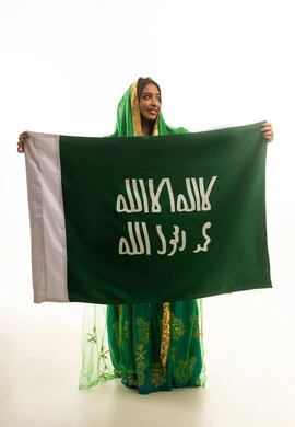امرأة سعودية بالزي التقليدي تحمل علم المملكة