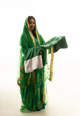 امرأة سعودية بالثوب الأخضر التقليدي تحمل العلم