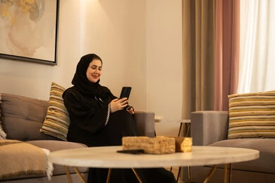 Saudi Woman with Smartphone in Modern Living Room