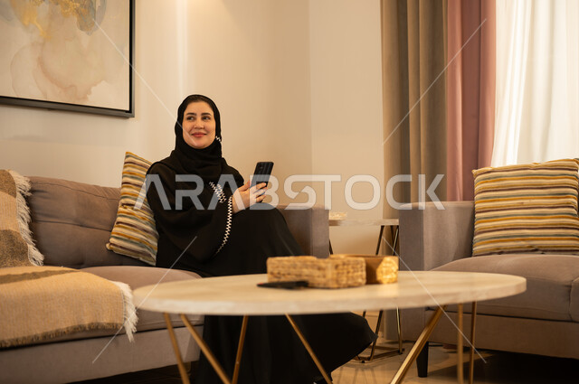 Saudi Woman in Abaya Using Smartphone at Home