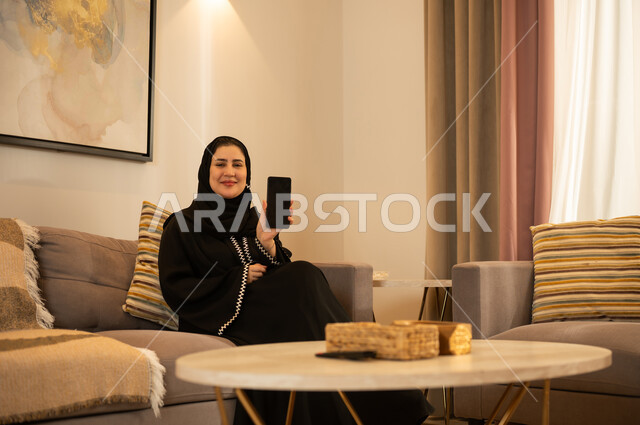 امرأة سعودية تحمل هاتف ذكي في غرفة معيشة