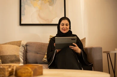 امرأة سعودية تستخدم جهاز لوحي في غرفة المعيشة