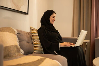 امرأة سعودية تستخدم الكمبيوتر المحمول في المنزل