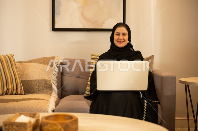 امرأة سعودية مع لابتوب في غرفة المعيشة