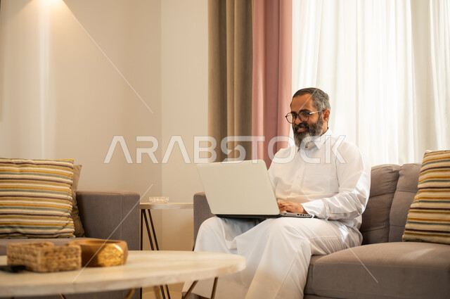 رجل سعودي يستخدم المحمول في غرفة معيشة عصرية