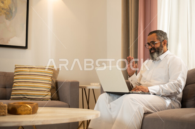 رجل سعودي يستخدم الكمبيوتر المحمول لمكالمة فيديو بالمنزل