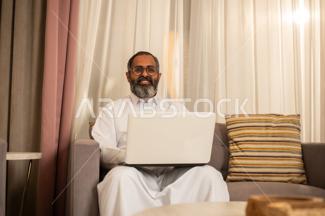 Saudi Man Using Laptop on Sofa at Home