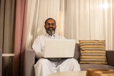 رجل سعودي يستخدم الحاسوب المحمول في المنزل