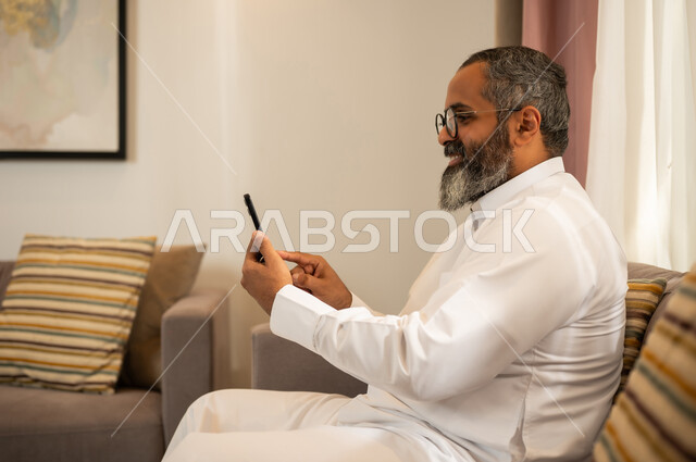 رجل سعودي يرتدي الثوب ويستخدم الهاتف الذكي
