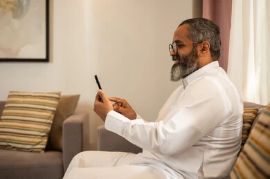 رجل سعودي يرتدي الثوب ويستخدم الهاتف الذكي