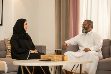 رجل وامرأة من السعودية يتحدثان في غرفة معيشة حديثة