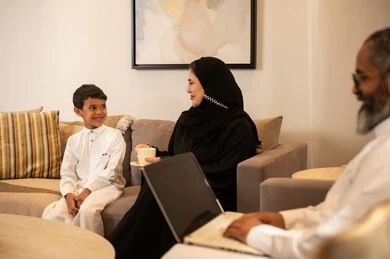 عائلة سعودية في غرفة المعيشة مع أب يستخدم اللابتوب