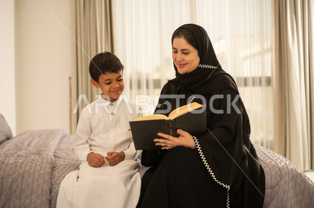 أم سعودية تقرأ كتاباً لابنها في المنزل