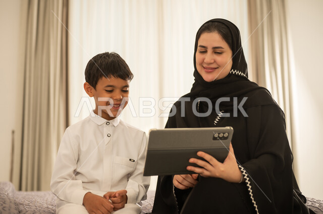 أم سعودية وابنها يستخدمان الجهاز اللوحي في المنزل