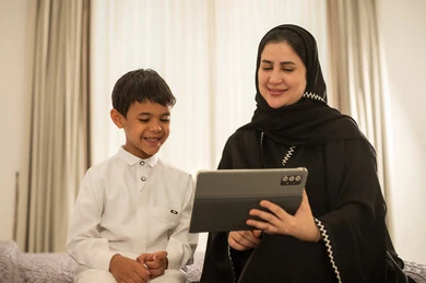 أم سعودية وابنها يستخدمان الجهاز اللوحي في المنزل