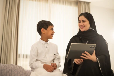 امرأة سعودية وطفل يستخدمان جهاز لوحي في المنزل