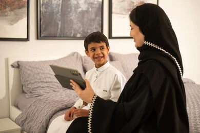 Saudi Mother and Son Using Tablet in Bedroom