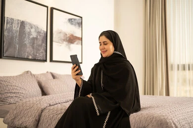 امرأة سعودية تستخدم الهاتف الذكي في غرفة نوم حديثة