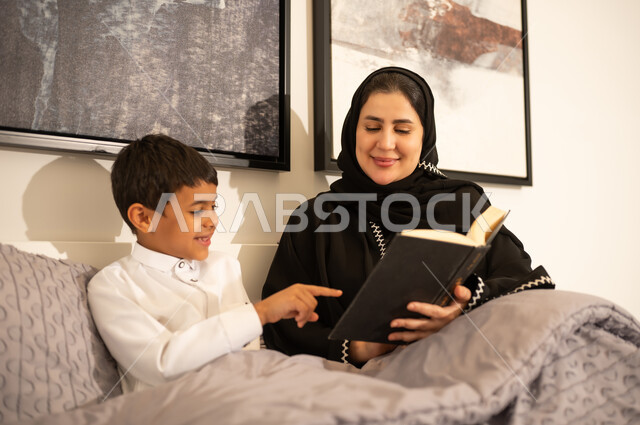 أم سعودية تقرأ كتاباً لابنها في غرفة النوم
