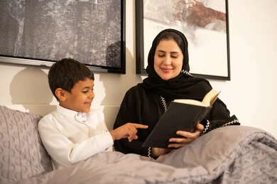 أم سعودية تقرأ كتاباً لابنها في غرفة النوم