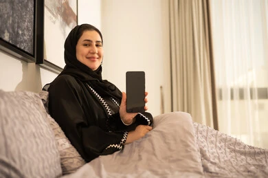 Saudi Woman in Bed Holding Smartphone Blank Screen