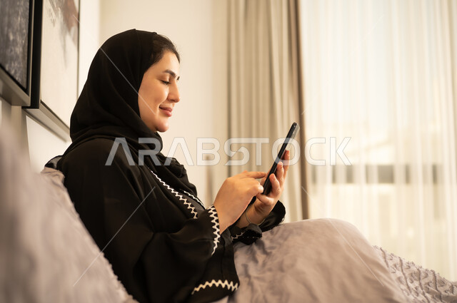 امرأة سعودية تستخدم الهاتف الذكي في غرفة النوم