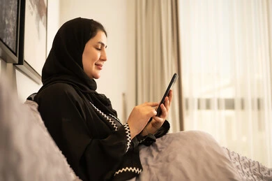 Saudi Woman Using Smartphone in Bed Indoors