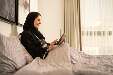 امرأة سعودية تستخدم جهاز لوحي في غرفة النوم
