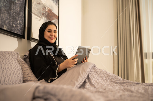 امرأة سعودية مع جهاز لوحي في غرفة النوم