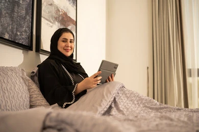 امرأة سعودية مع جهاز لوحي في غرفة النوم