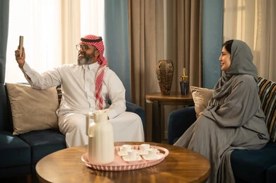 رجل وامرأة من السعودية يلتقطان سيلفي في غرفة المعيشة