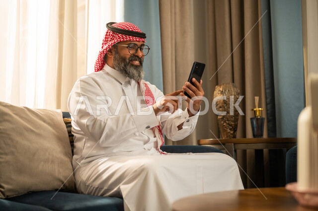 رجل سعودي بالزي التقليدي يستخدم هاتف ذكي