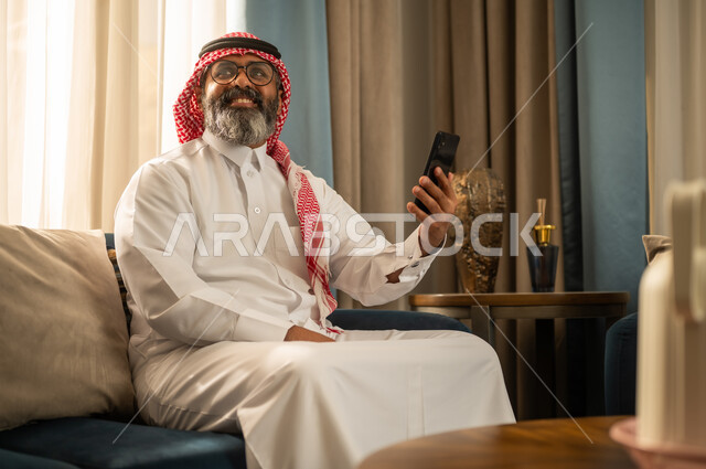 رجل سعودي يستخدم الهاتف الذكي في غرفة المعيشة