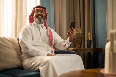 رجل سعودي يستخدم الهاتف الذكي في غرفة المعيشة