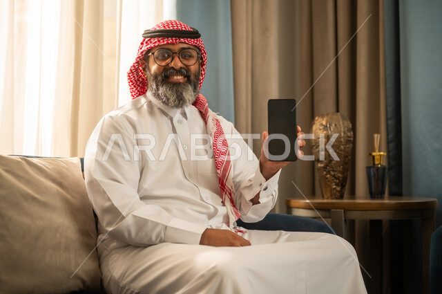 رجل سعودي يحمل هاتف ذكي بشاشة سوداء فارغة