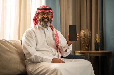 رجل سعودي يحمل هاتف ذكي بشاشة سوداء فارغة