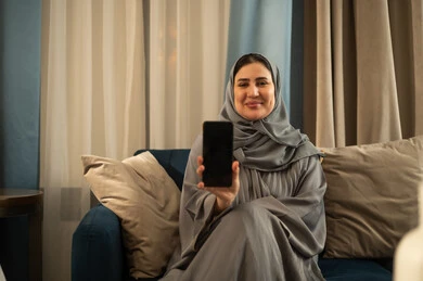 امرأة سعودية تحمل هاتف ذكي في غرفة المعيشة