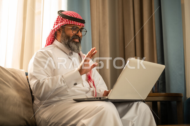 Saudi Man on Laptop Video Call Waving at Home
