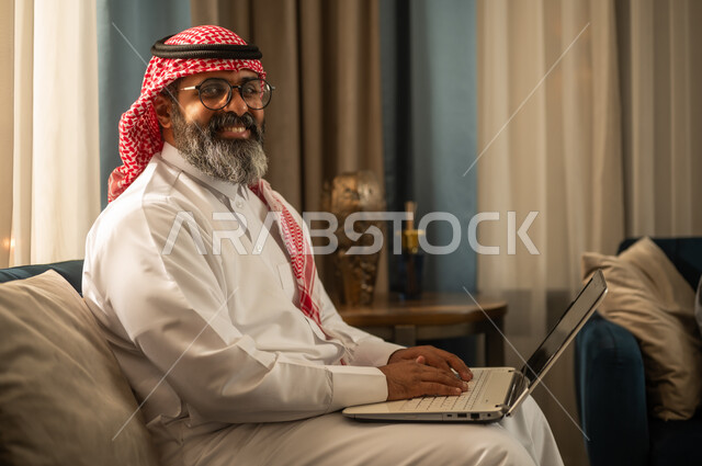 Saudi Man Using Laptop in Traditional Dress at Home