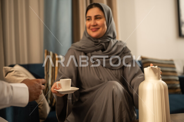 امرأة سعودية بالعباءة تقدم القهوة في المنزل