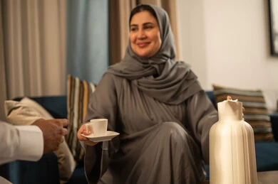 امرأة سعودية بالعباءة تقدم القهوة في المنزل