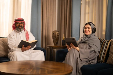 رجل وامرأة من السعودية مع كتاب وجهاز لوحي