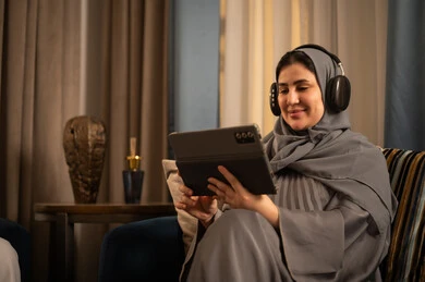 Saudi Woman Using Tablet with Headphones at Home