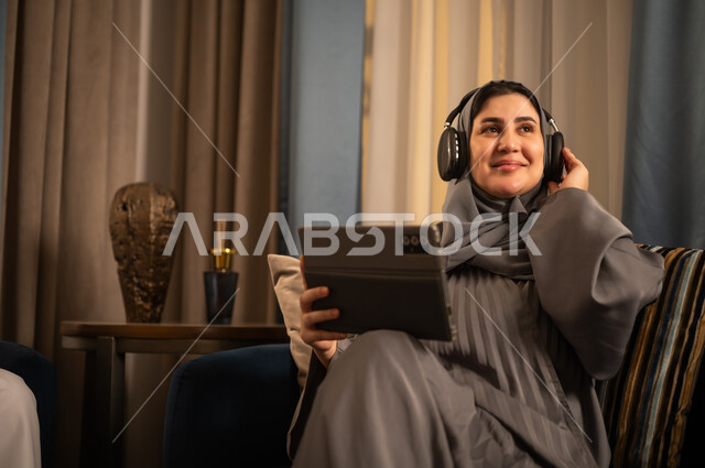 امرأة سعودية تستخدم الجهاز اللوحي والسماعات في المنزل
