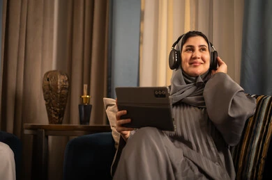 امرأة سعودية تستخدم الجهاز اللوحي والسماعات في المنزل