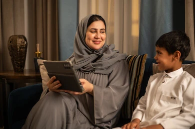 أم سعودية وابنها يستخدمان جهازاً لوحياً في المنزل