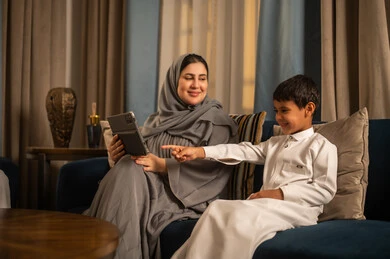 Saudi Mother and Son Using Tablet in Living Room